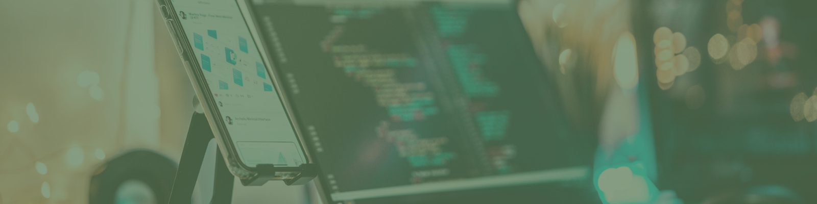 A smartphone displaying a Melbourne web design website stands on a desk next to a computer screen with lines of code, reminiscent of a café serving up creativity and smashed avo delights.
